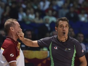 Referee Juan Garcia  covers the mouth of Venezuela's coach Nestor Garcia while he was celebrating a point against Canada during their 2015 FIBA Americas Championship men's Olympic semifinal match  in Mexico City on Friday. (AFP PHOTO/ Yuri CORTEZ)
