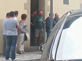 In this image from TV taken on Sept. 11, 2015, and made available Sept. 12, 2015, authorities lead suspect Miguel Angel Munoz, centre in green, out of a building, in Grandas de Salime, northwest Spain. (Rocio Ferreira via APTN)