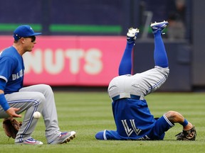 Blue Jays shortstop Troy Tulowitzki (left) drops the ball while falling to the grass after colliding with center fielder Kevin Pillar when they both tried to field a fly ball in  the second inning of the first game of a doubleheader against the Yankees on Saturday in New York. (AP/PHOTO)