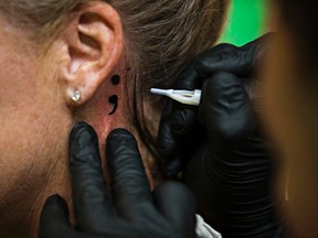 Lisa Atkins gets a tattoo from Kevin Shuttleworth of Keltic Tattoo Parlor during the Edmonton Semicolon Tattoo event at the Prince of Wales Armoury in Edmonton, Alta. on Sunday, Sept. 13, 2015. The event, which is inspired by Project Semicolon in the United States, brings together a collective of local tattoo shops and artists and various community organizations to physically mark the semicolon icon on hundreds of participants. The event was held in support of Momentum Walk-In Counselling and mental health awareness. Codie McLachlan/Edmonton Sun/Postmedia Network