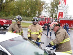 Capt. Dale Milligan (red helmet) demonstrates how hydraulic rescue tools like the jaws of life is used to hastily remove doors and other parts of a vehicle in order to extricate crash victims.