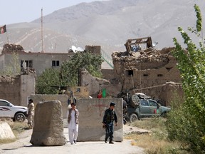 An Afghan policeman, right, walks outside a prison building after an attack in Ghazni province, Afghanistan, on Sept. 14, 2015. (REUTERS/Stringer)