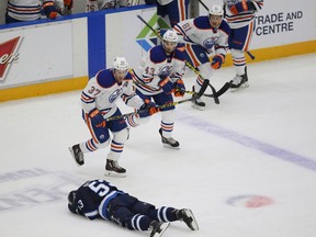Edmonton Oilers players come onto the ice as Winnipeg Jets’ defenceman Jan Kostalek lies injured during the first period Monday. Kostalek left the game with an upper-body injury and didn’t return.
