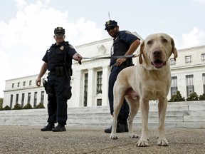 Police officers stand with their dog outside the Federal Reserve patrol in front  of the building with their dog Brodie in Washington September 1,  2015. (REUTERS/Kevin Lamarque)