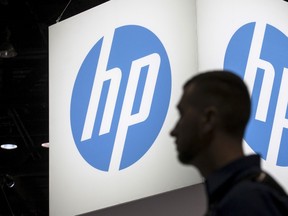 An attendee at the Microsoft Ignite technology conference walks past the Hewlett-Packard (HP) logo in Chicago, Illinois, in this file photo from May 4, 2015. Hewlett-Packard Co, which plans to split into two listed companies this year, said it expected to cut about 33,300 jobs over three years as the tech pioneer adjusts to falling demand. REUTERS/Jim Young/Files