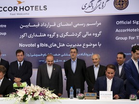 Sebastien Bazin, chairman and CEO of AccorHotels, a French hotel chain, seated left, and Mehdi Jahangiri, chairman of Iran's Aria Ziggurat Tourism Development Company, seated right, sign an agreement at a newly build Novotel hotel near International Imam Khomeini Airport. (AP Photo/Vahid Salemi)