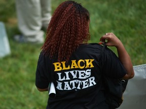 A woman wears a shirt with 'Black Lives Matter' during a memorial service for slain 18 year-old Michael Brown Jr. on August 9, 2015 at the Canfield Apartments in Ferguson, Missouri.   AFP PHOTO / MICHAEL B. THOMAS