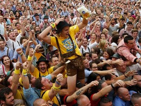 A visitor celebrates as he drinks one of the first mugs of beer after the tapping of the first barrel during the opening ceremony for the 180th Oktoberfest at the Hofbraeu tent in Munich in this September 21, 2013 file photo. REUTERS/Michael Dalder/Files