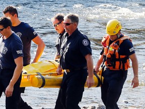 Belleville firefighters carry a woman along the Moira River's eastern bank in downtown Belleville, Ont. after city police pulled her from the water Wednesday, September 16, 2015. Police said the woman's foot became lodged between rocks after she went swimming north of Victoria Avenue. Hastings-Quinte paramedics took her to Belleville General Hospital as a precaution. Police advise against swimming in the area. Luke Hendry/Belleville Intelligencer/Postmedia Network