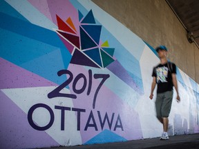 A man walks past a large mural on the walls of the Metcalfe Street/Queensway overpass promoting the events taking place in Ottawa to celebrate the 150th anniversary of Canada. Wednesday September 16, 2015. Errol McGihon/Ottawa Sun/Postmedia Network
