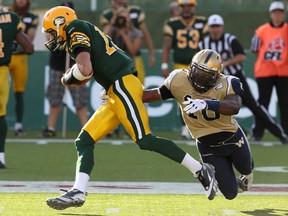 Eskimos quarterback Mike Reilly #13 is grabbed by Henoc Muamba #10 as the Edmonton Eskimos take on the Winnipeg Blue Bombers in the first quarter of their game at Commonwealth Stadium in Edmonton, Alta., on Saturday, Sept. 14, 2013. Ian Kucerak/Edmonton Sun/QMI Agency