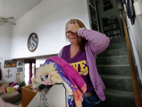 Sabrina Jose holds her head as she walks past family photos lining a stairwell after grabbing some of her daughter's possessions during a brief, escorted visit to her home Wednesday, Sept. 16, 2015, in Middletown, Calif. Jose's still-standing home was surrounded by the remains of houses burned to the ground in a wildfire days earlier. Aided by drought, the flames have consumed more than 109 square since the fire sped Saturday through rural Lake County, less than 100 miles north of San Francisco. (AP Photo/Elaine Thompson)