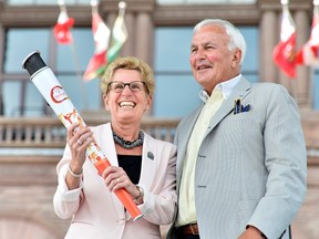 Ontario Premier Kathleen Wynne receives an honourary Pan Am Games torch from former Ontario premier David Peterson, chair of the board that is organizing the Toronto 2015 Pan Am/Parapan Am Games during a ceremony at Queen's Park in Toronto, Thursday, July 9, 2015. THE CANADIAN PRESS/Nathan Denette