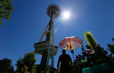 FILE - In this July 1, 2015, file photo, a balloon vendor sets up shot next to the Space Needle in Seattle. The Space Needle is a popular tourist attraction in Seattle.  (AP Photo/Ted S. Warren, File)