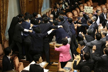Japanese lawmakers scuffle during a committee voting of security bills as opposition lawmaker Taro Yamamoto, right top, holds up a banner reading "The day Liberal Democratic Party is dead" at at the upper house of the parliament in Tokyo, Thursday, Sept. 17, 2015. (AP Photo/Eugene Hoshiko)