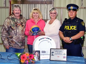 On behalf of Windmill Family Campground, Robert and Charlotte Burnham (left), of Gowanstown, accept an Automatic External Defibrillator (AED) from Jan Vogel, a member on the board of directors for the Dave Mounsey Memorial Fund, and Const. James Choi of the Ontario Provincial Police (OPP), during a ceremony Sept. 12 outside Fullarton. GALEN SIMMONS/MITCHELL ADVOCATE