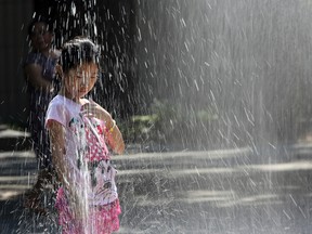 In this Aug. 17, 2015 file photo, a child plays in the sprinklers of Seward park in New York as temperatures are expected to reach into the 90s in the New York metro area. Earth’s record breaking heat is sounding an awful lot like a broken record. The National Oceanic and Atmospheric Administration announced Thursday that last month, this past summer and the first eight months of 2015 all smashed global records for heat. (AP Photo/Mary Altaffer, File)