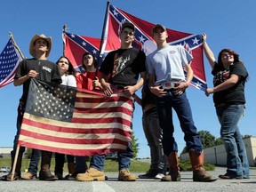Christiansburg High School students bearing American and Confederate flags gather in a shopping center parking lot after being suspended from school property in Christiansburg, Va. Thursday, Sept. 17, 2015. Roughly 20 students at the Virginia high school received a one-day suspension for wearing clothing displaying the Confederate flag. A rally was also organized outside the school Thursday to protest a new school policy banning vehicles with Confederate symbols from its parking lot. (Matt Gentry /The Roanoke Times via AP)