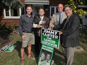 Arthur Milnes, with hammer, is joined by Kingston and the Islands candidates, from right, Daniel Beals of the New Democratic Party, Conservative candidate Andy Brooke and Robert Kiley on behalf of Green Party candidate Nathan Townend to set up a sign honouring former United States president Jimmy Carter's fight with cancer in Kingston. (Elliot Ferguson/The Whig-Standard)