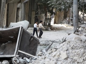 Boys walk through damage from what activists said was an airstrike by forces loyal to Syria's President Bashar al-Assad  in al-Sukari neighbourhood of Aleppo, Syria September 16, 2015. REUTERS/Abdalrhman Ismail