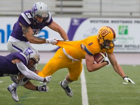 Queen's Golden Gaels receiver Rudy Uhl is tackled by Western Mustangs defensive backs Malcolm Brown and Christian Collarile during an Ontario University Athletics football game at TD Stadium in London on Saturday. Western won the game 48-25. (Craig Glover/Postmedia Network)
