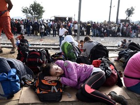 A girl sleeps next to the railway tracks as other people wait to pass from the northern Greek village of Idomeni to southern Macedonia, Sunday, Sept. 20, 2015. More than 2,000 refugees and economic migrants wait at the small village of about 100 inhabitants every day to be let into Macedonia, from where they continue through Serbia and Hungary to seek asylum in wealthier European countries. (AP Photo/Giannis Papanikos)