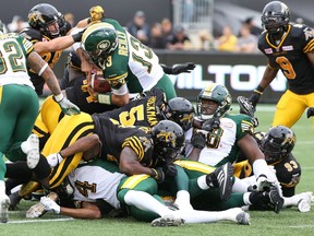 Edmonton Eskimos quarterback Mike Reilly (13) carries the ball during the first half in Hamilton, Ontario against the Hamilton Tiger-Cats on Saturday. PHOTO CREDIT: THE CANADIAN PRESS