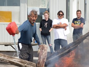 Pierre George pours gasoline over a fire as he and a group of fellow band members erect a barricade at the entrance of the former army camp, Camp Ipperwash, to keep approaching Kettle and Stony Point First Nation members from ending a celebratory march at the camp in Ipperwash, Ont. on Sunday September 20, 2015. (CRAIG GLOVER, The London Free Press)