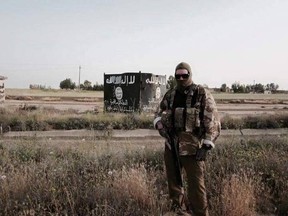 Canadian volunteer combat medic, Justin (not his real name,) stands in front of a water-tank emblazoned by the Islamic State. 
OTTAWA SUN/ COURTESY OF 'JUSTIN'
