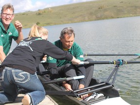 Rustlers rowing coach Peter Walsh and a team member help Vermilion-Lloydminster MLA Richard Starke into a canoe at the Vermilion Provincial Park on Thursday.