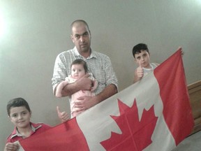 Members of a Syrian family, from, front left, Kousay, 7, his brother Ouday, 8 and their father Marwan holding their sister Masey, six months, pose with a Canadian flag earlier this month in Beirut Lebanon during a visit to the Canadian Visa Office. The Syrian family is due to arrive in Kingston later this week.  Submitted Photo/The Kingston Whig-Standard/Postmedia Network