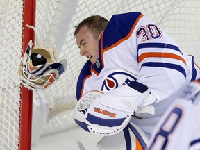 Goalie Ben Scrivens from the Edmonton Oilers makes a save with his face as he took a shot off his mask, knocking it off in the process as he and his team took on the Calgary Flames in pre-season NHL hockey action at the Scotiabank Saddledome in downtown Calgary, Alta. on Monday September 21, 2015. Stuart Dryden/Calgary Sun/Postmedia Network