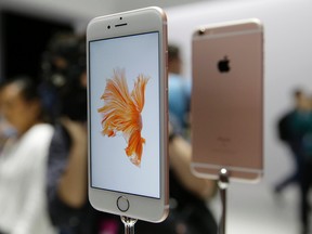 In this Sept. 9, 2015 photo, people look over the new Apple iPhone 6s models during a product display following an Apple event in San Francisco. Photography gets even better with Apple's new iPhones, making them worth getting for $100 more than last year's models.(AP Photo/Eric Risberg)