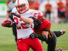 Medway?s Brent Craig keeps his feet churning and scores a touchdown while dragging Jacob Reitzel of Saunders during their United Way football tournament game at TD Stadium on Tuesday. The Cowboys won 21-7. (MIKE HENSEN, The London Free Press)