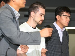 Arthur Patterson, center, an American charged with murdering a Seoul university student in 1997, is escorted by South Korean police officers upon his arrival at Incheon International airport in Incheon, South Korea, Wednesday, Sept. 23, 2015. Patterson has been extradited to South Korea to face a new trial. The Justice Ministry says that Patterson arrived from Los Angles on Wednesday. (Im Hun-jung/Yonhap via AP)