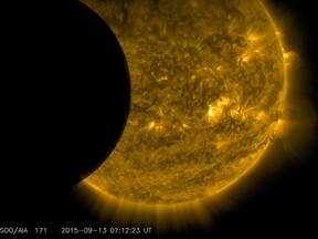This Sept. 13, 2015 image provided by NASA shows the moon, left, and the Earth, top, transiting the sun together, seen from the Solar Dynamics Observatory. A total lunar eclipse will share the stage with a so-called supermoon Sunday evening, Sept. 27, 2015 as seen from the United States. (NASA/SDO via AP)