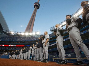 The New York Yankees pause during a moment of silence for former Yankees great Yogi Berra prior to their game against the Blue Jays on Wednesday night in Toronto. (STAN BEHAL/TORONTO SUN)