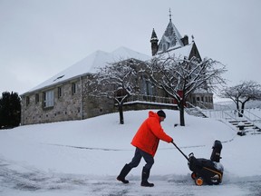 A man clears a road of snow in Pitlochry, central Scotland February 23, 2015. REUTERS/Russell Cheyne