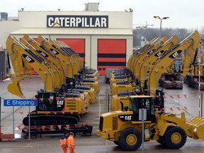 Workers walk past Caterpillar excavator machines at a factory in Gosselies, in this file photo taken February 28, 2013. Caterpillar Inc said it could cut up to 10,000 jobs through 2018 as part of its restructuring and cost reduction plans to save up to $1.5 billion annually.  (REUTERS/Eric Vidal/Files)
