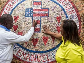 Abe Makiti (L) signs a memorial in front of Emanuel AME Church JULY 31, 2015 in Charleston, South Carolina. Earlier in the morning, Dylan Roof, the shooter in the June 17 massacre was arraigned on 33 federal charges, including federal hate crimes.  Sean Rayford/Getty Images/AFP