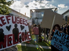 A demonstrator displays a placard reading "refugees welcome" during a protest outside the chancellery as a special meeting of the German government with the Prime Ministers of Germany's Federal States focusing on the refugee crisis was underway at the Chancellery in Berlin on September 24, 2015. (AFP PHOTO/JOHN MACDOUGALL)