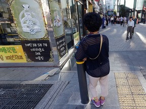 In this Sept. 17, 2015 photo, an elderly woman stands at a small, bustling plaza in front of the Piccadilly theater in Seoul, South Korea. (AP Photo/Ahn Young-joon)