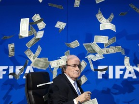 A picture taken on July 20, 2015 shows FIFA president Sepp Blatter looking on as fake dollar notes fly around him, thrown by a British comedian during a press conference at the FIFA world-body headquarter's in Zurich. (AFP PHOTO / FABRICE COFFRINI)