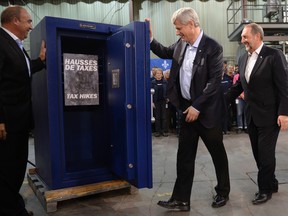 Conservative Leader Stephen Harper closes the door on a safe containing a poster during a photo opportunity in Riviere du Loup on Friday, September 25, 2015. THE CANADIAN PRESS/Ryan Remiorz
