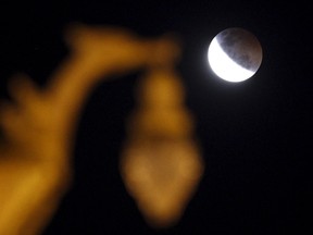 A shadow falls on the moon after a total lunar eclipse, near a swan statue in Nakhon Pathom province on the outskirts of Bangkok April 4, 2015.  REUTERS/Chaiwat Subprasom