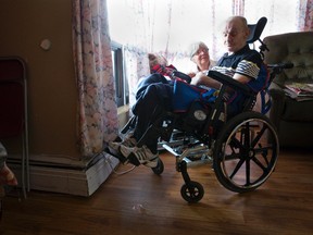 Lynda Windsor crouches next to her brother, Gary Dedrick, by the window in his room at a long-term care facility in London Friday. (CRAIG GLOVER, The London Free Press)