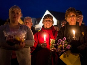 Mourners hold a candlelit vigil in remembrance of Carol Culleton, Anastasia Kuzyk and Natalie Warmerdam in Wilno, Ont. on Friday, Sept. 25, 2015. Basil Borutski has been charged with three counts of first-degree murder in the separate slayings of the three women, whose deaths sparked a lockdown and manhunt in an ordinarily peaceful part of eastern Ontario. THE CANADIAN PRESS/Justin Tang