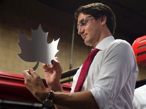 Liberal leader Justin Trudeau holds up a maple leaf shape cut out of a sheet of metal prior to speaking at a campaign stop in Brampton, on Sept. 25, 2015. (THE CANADIAN PRESS/Adrian Wyld)