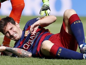 Barcelona's Lionel Messi grimaces as he lies on the pitch after injuring his left knee during Spanish first division soccer action against Las Palmas at Camp Nou stadium in Barcelona, Spain, on Saturday, Sept. 26, 2015. (Sergio Perez/Reuters)