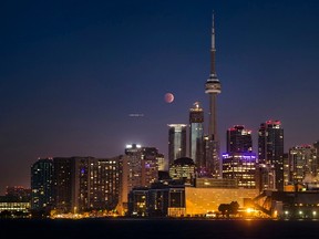 The moon turns orange during a total lunar eclipse behind the CN Tower and the skyline during moonset in Toronto October 8, 2014. The eclipse is also known as a "blood moon" due to the coppery, reddish color the moon takes as it passes into Earth's shadow. The total eclipse is the second of four over a two-year period that began April 15 and concludes on Sept. 28, 2015. The so-called tetrad is unusual because the full eclipses are visible in all or parts of the United States, according to retired NASA astrophysicist Fred Espenak.  REUTERS/Mark Blinch (CANADA - Tags: SOCIETY ENVIRONMENT CITYSCAPE)